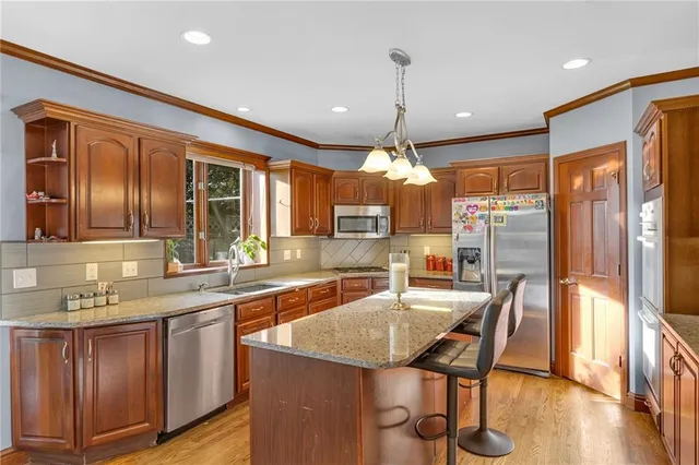 a kitchen with stainless steel appliances granite countertop a kitchen island hardwood floor sink stove dining table and chairs