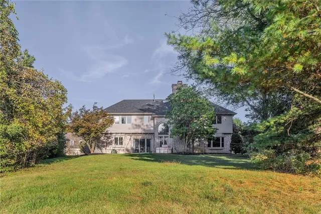 a front view of a house with a garden and trees