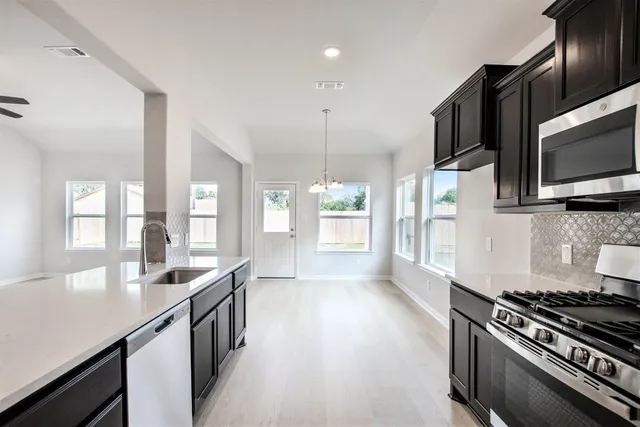 a kitchen with granite countertop stainless steel appliances a sink cabinets and a wooden floor