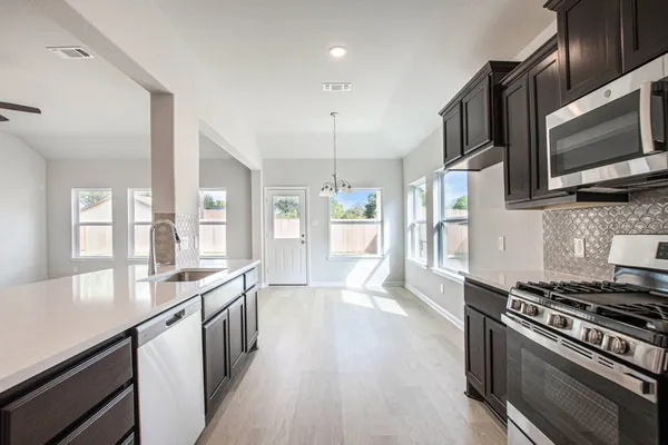 a kitchen with stainless steel appliances granite countertop a stove top oven microwave and refrigerator