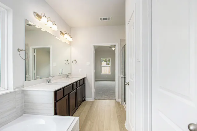 a spacious bathroom with a granite countertop sink a mirror and a shower