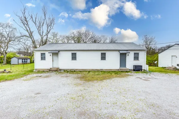 a view of a house with a yard and large tree