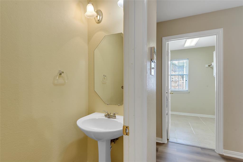 1404 Ranch Hill Drive Irving, TX 75063 - Photo 18 of 31 Pedestal sink with brass-finish faucet, octagonal mirror, and wall-mounted light fixture