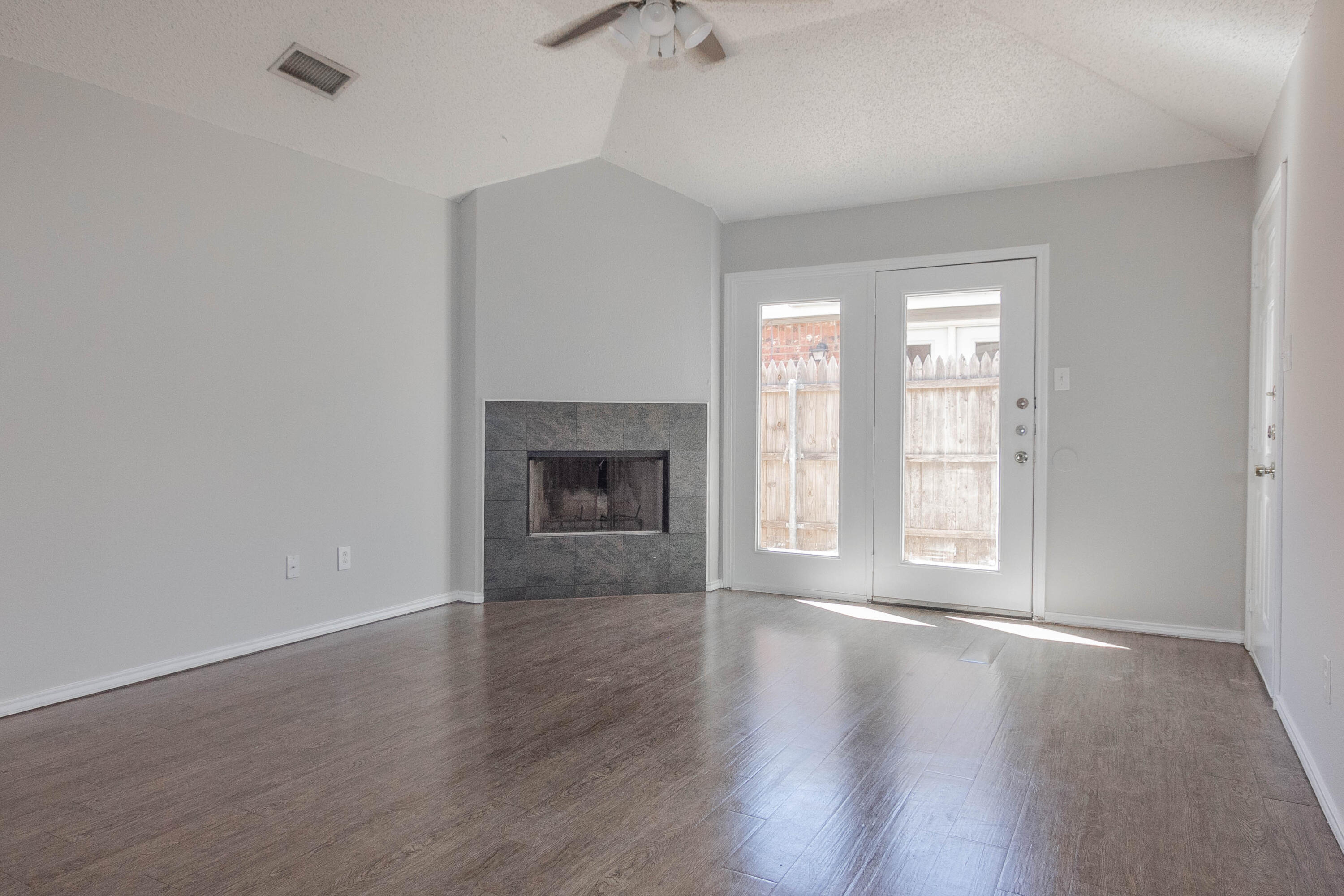 2409 87th Street, Unit B Lubbock, TX 79423 - Photo 3 of 11 an empty room with wooden floor fireplace and windows