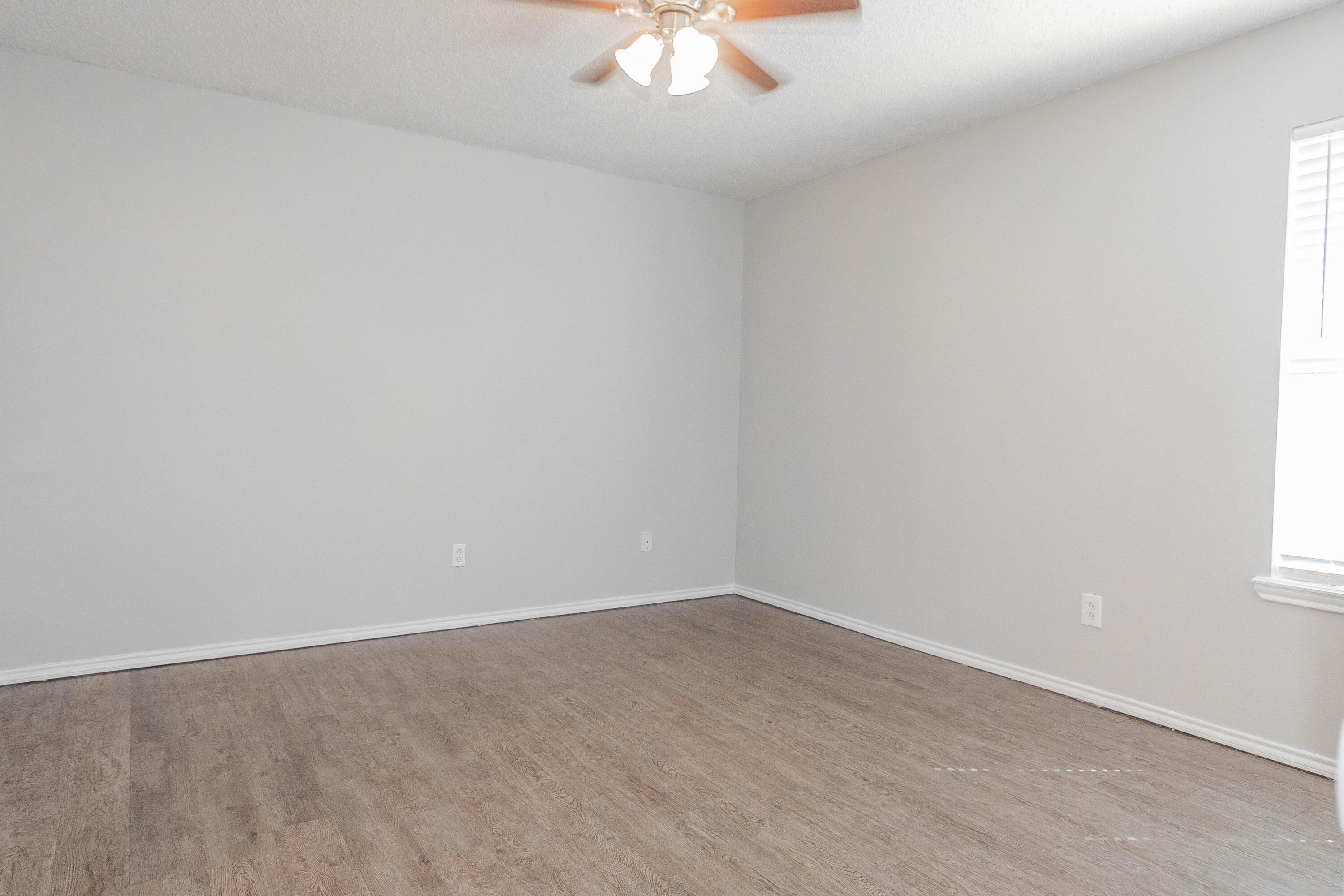2409 87th Street, Unit B Lubbock, TX 79423 - Photo 8 of 11 an empty room with a chandelier fan and windows