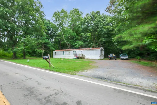 a view of a house with a yard and large trees