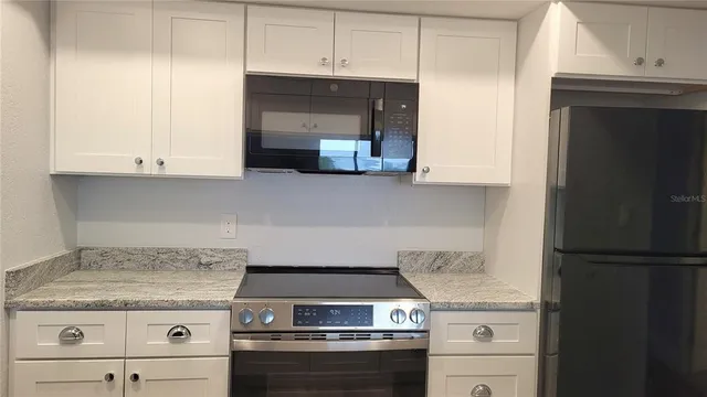 a kitchen with stainless steel appliances granite countertop a stove a sink and a microwave