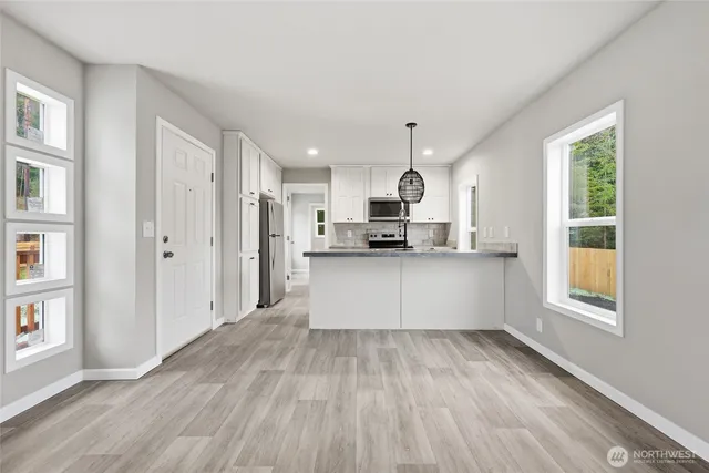 a large white kitchen with kitchen island a refrigerator wooden floor and window