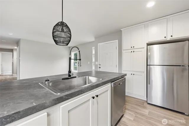 a kitchen with granite countertop a sink stainless steel appliances and cabinets
