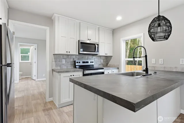 a kitchen with kitchen island granite countertop a stove a sink and a microwave