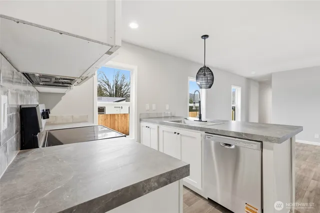 a kitchen with white cabinets and wooden floor