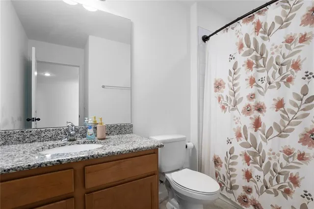 a bathroom with a granite countertop sink a toilet and shower curtain