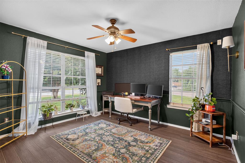 100 Radecke Road Krum, TX 76249 - Photo 8 of 29 Spacious room featuring dark-toned walls with wainscoting, wood-finish flooring, and a ceiling fan with integrated lighting