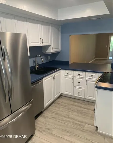 a kitchen with granite countertop a refrigerator sink and cabinets