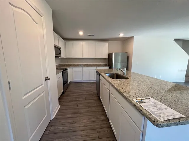 a kitchen with kitchen island granite countertop a sink and wooden floor