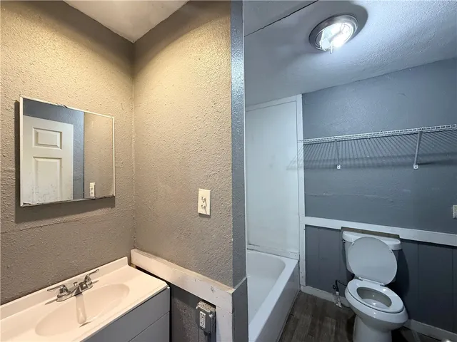 a bathroom with a granite countertop toilet sink and mirror