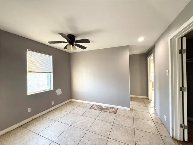 a view of an empty room and window & a ceiling fan