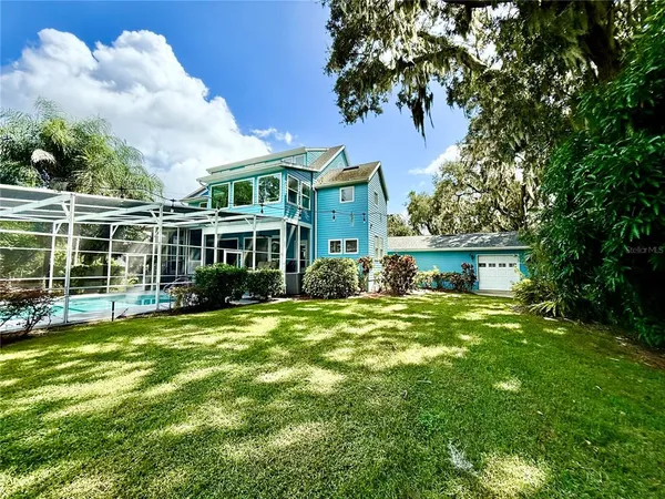 a view of a big yard with plants and large trees