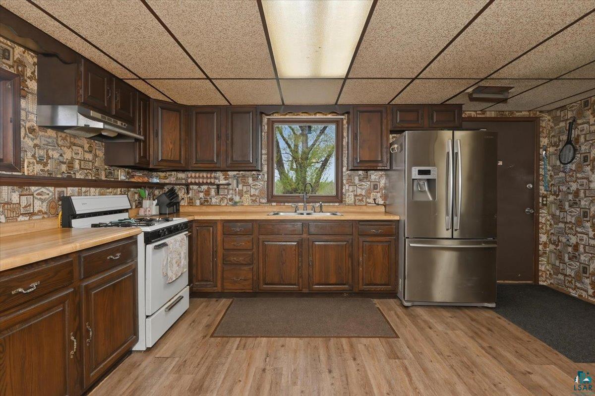 5190 County Road M Gordon, WI 54838 - Photo 9 of 31 Kitchen featuring wood-finish flooring, dark wood cabinetry, and a stainless steel refrigerator