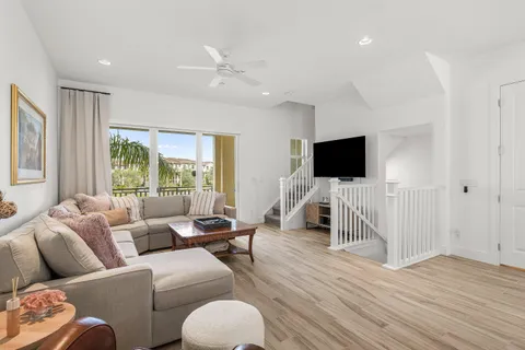 a large white kitchen with a stove a sink a refrigerator and white cabinets with wooden floor