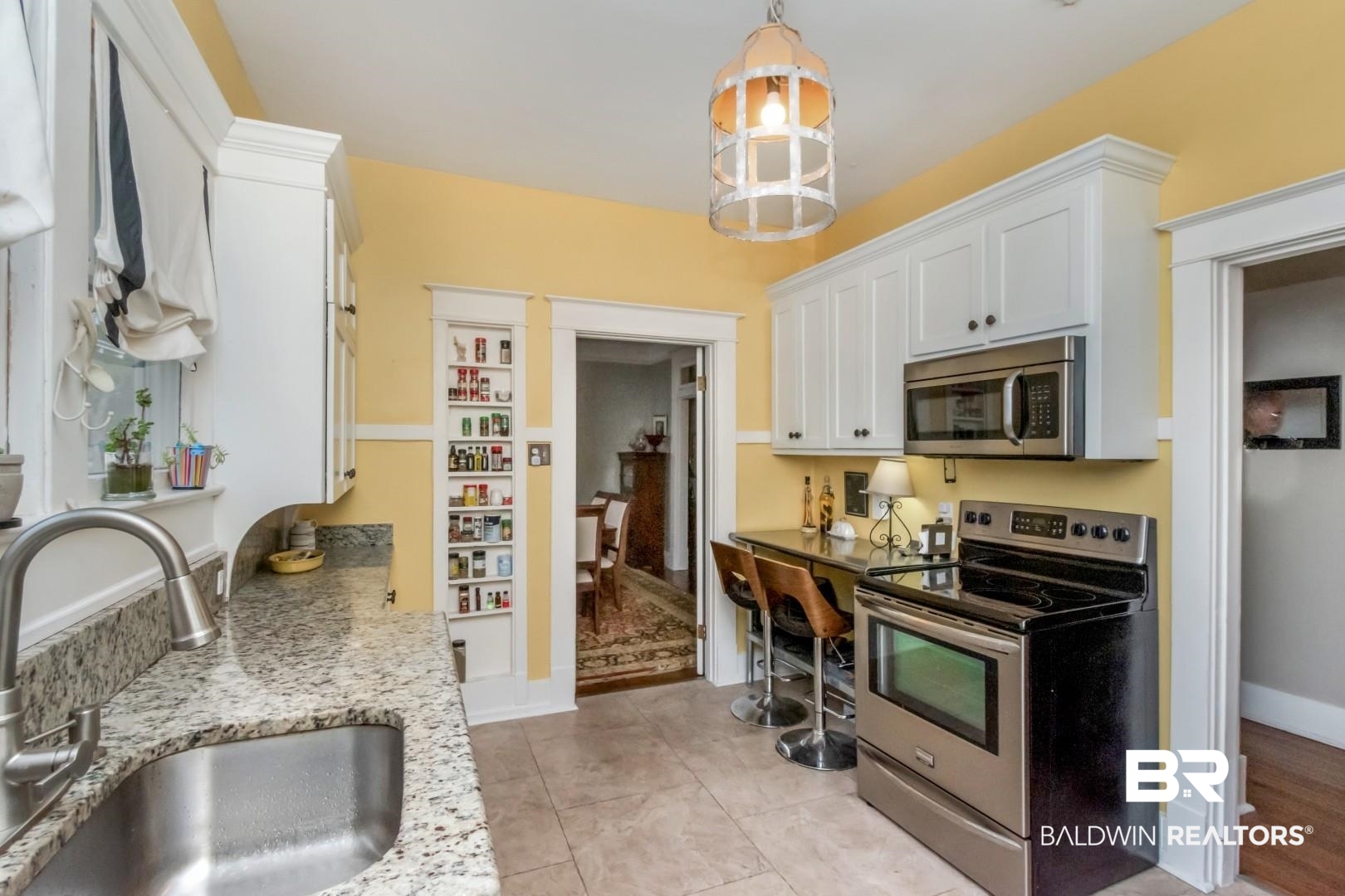 135 Silverwood Street Mobile, AL 36607 - Photo 10 of 32 Kitchen with appliances with stainless steel finishes, white cabinets, decorative light fixtures, light stone countertops, and light tile patterned floors
