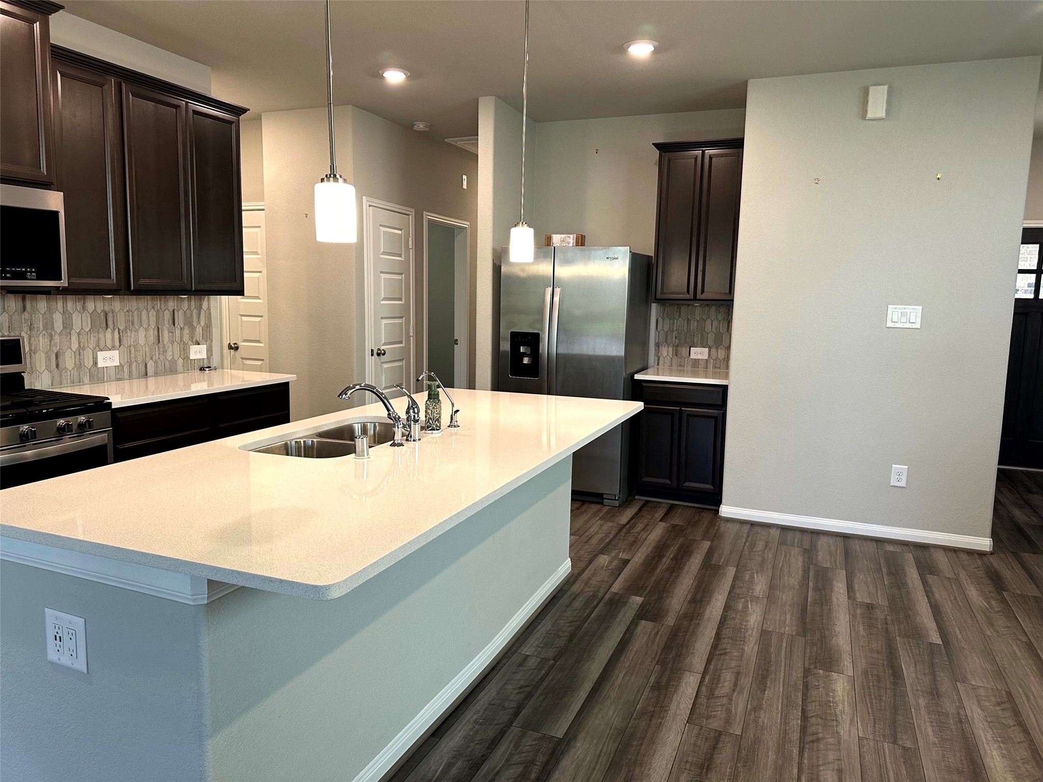 7072 Silverleaf Oak Street Conroe, TX 77304 - Photo 4 of 18 Kitchen boasts stainless steel appliances, quartz counters, and pendant lighting.