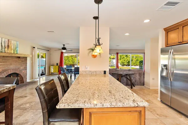 a kitchen with stainless steel appliances granite countertop sink stove refrigerator dining table and chairs