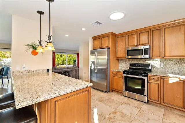 a kitchen with kitchen island granite countertop a sink stainless steel appliances and cabinets