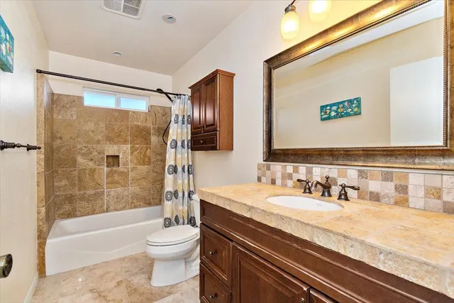 a bathroom with a granite countertop sink toilet and shower