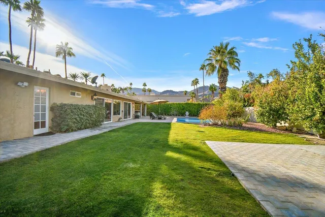 a view of a patio with couches table and chairs under an umbrella with a small yard