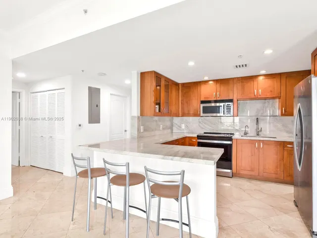 a kitchen with stainless steel appliances granite countertop a refrigerator a sink dishwasher a stove with wooden cabinets