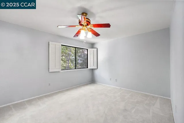 an empty room with windows and fan