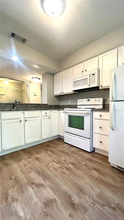 5324 Southwest 88 Court Gainesville, FL 32608 - Photo 7 of 21 a kitchen with stainless steel appliances granite countertop a stove a sink and white cabinets with wooden floor