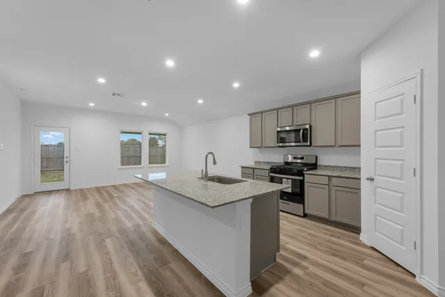 a kitchen with stainless steel appliances granite countertop a stove a sink and a refrigerator