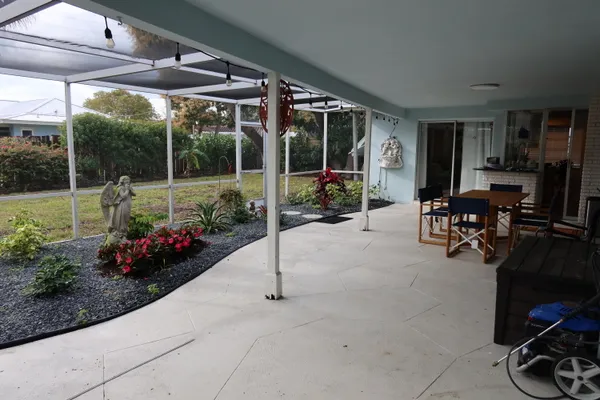 a view of a patio with table and chairs potted plants and floor to ceiling window