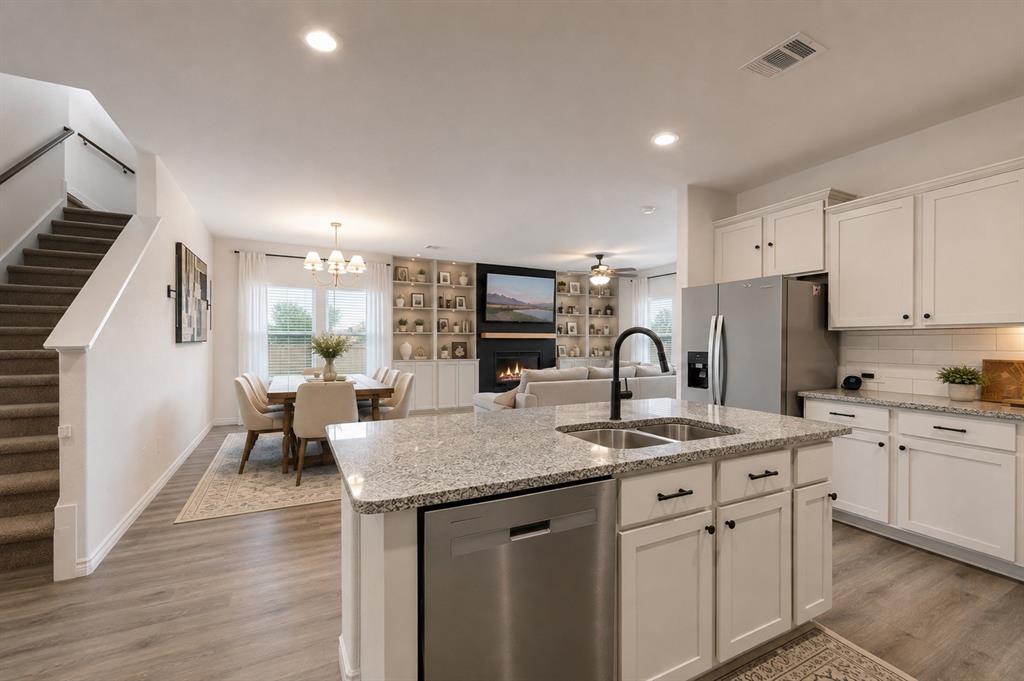 9828 Quail Pointe Road Aubrey, TX 76227 - Photo 17 of 23 Kitchen featuring white cabinetry, stainless steel appliances, granite countertops, and a dual-basin sink with a matte black faucet