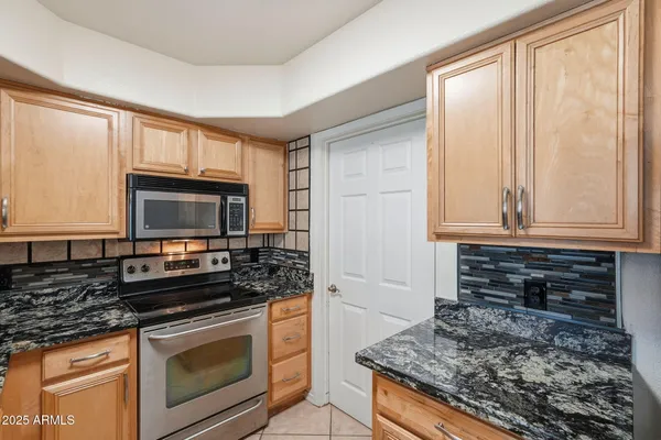 a kitchen with granite countertop a sink a stove a microwave and cabinets