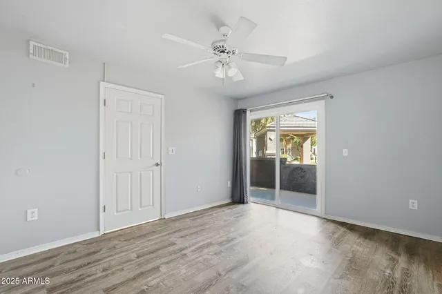 a view of an empty room with window and chandelier fan
