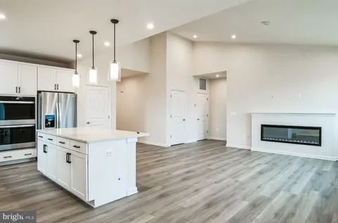 a kitchen with stainless steel appliances granite countertop a stove a refrigerator and a oven with wooden floor