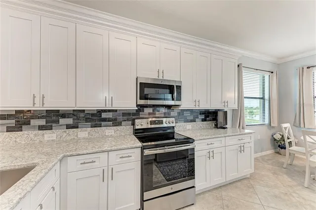 a kitchen with granite countertop white cabinets and stainless steel appliances