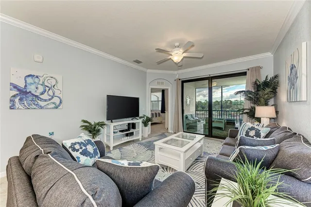 a living room with furniture floor to ceiling window and a flat screen tv