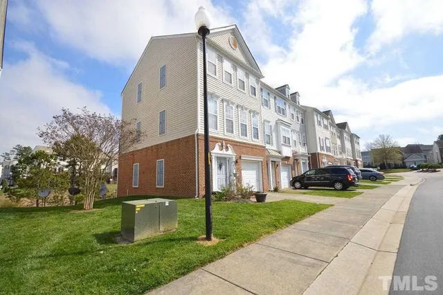 a view of a white house next to a yard with big trees