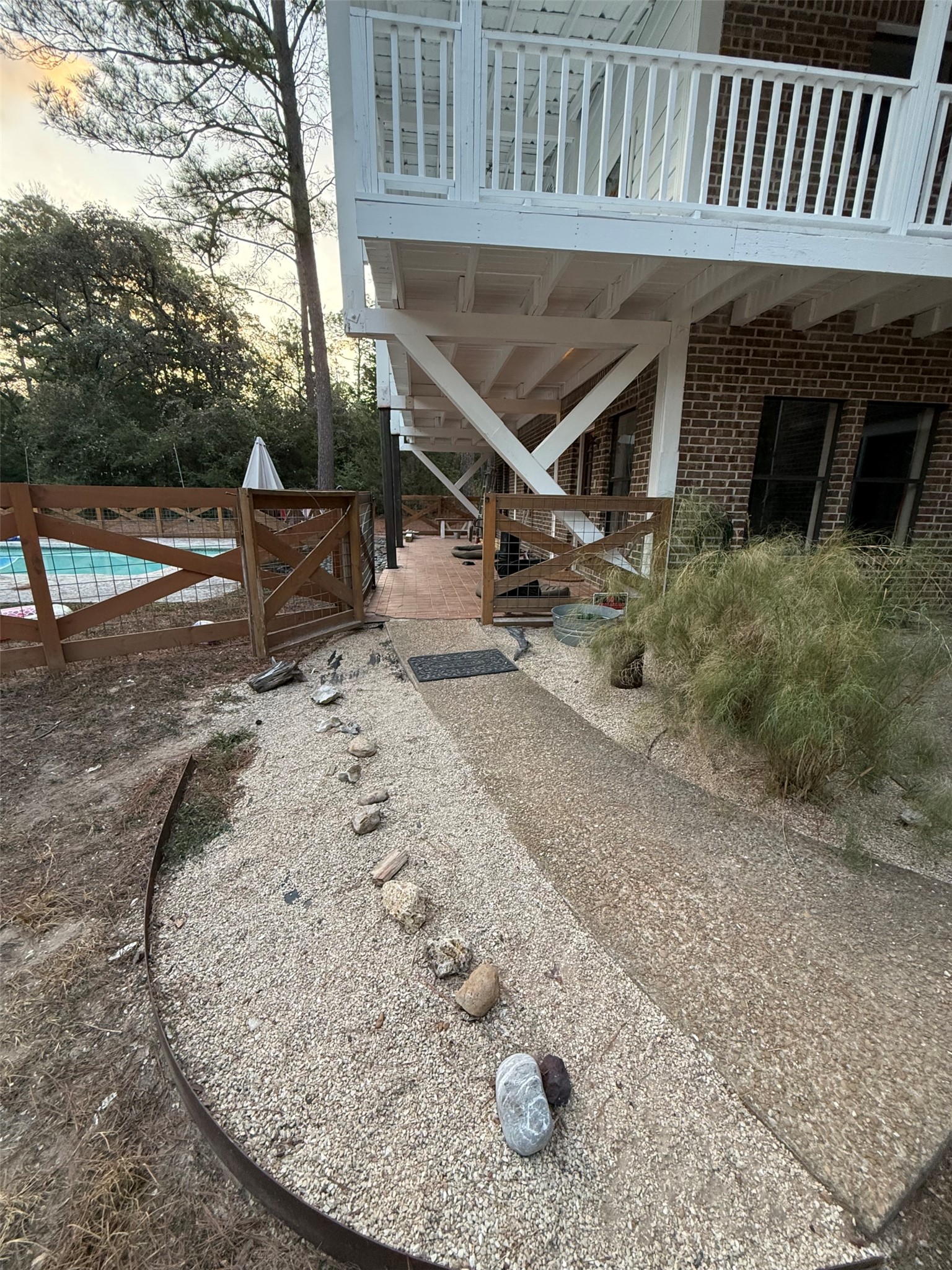 363 Porter Road Bastrop, TX 78602 - Photo 6 of 37 A pathway winds past timeless brick exterior walls toward a gated pool enclosure.