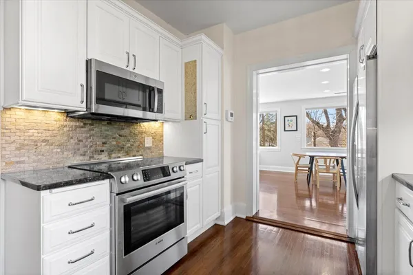 a kitchen with granite countertop a stove and a microwave