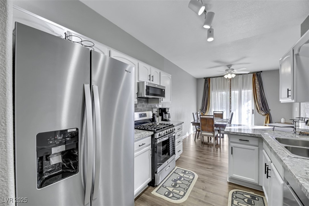 2907 Rio Sonora Court Henderson, NV 89074 - Photo 13 of 35 Kitchen featuring stainless steel appliances, white cabinets, light wood finished floors, track lighting, and a ceiling fan