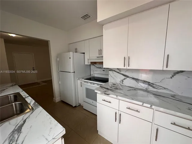 a kitchen with a refrigerator sink and cabinets