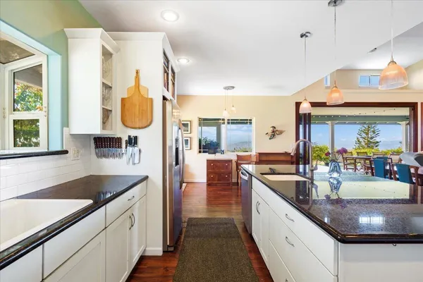 a kitchen with stainless steel appliances granite countertop a sink a stove and a wooden floors