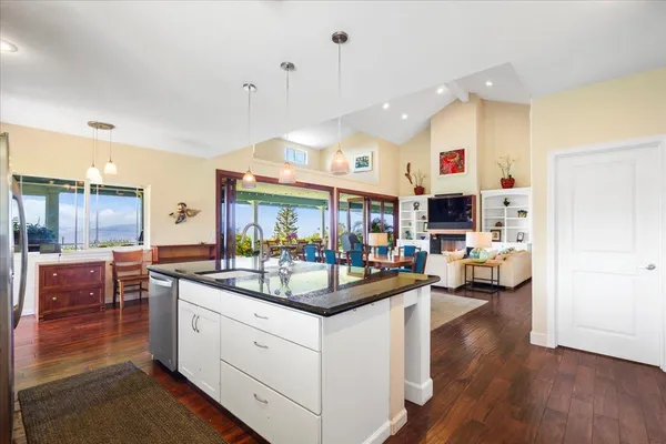 a kitchen with stainless steel appliances kitchen island granite countertop a stove and a view of living room