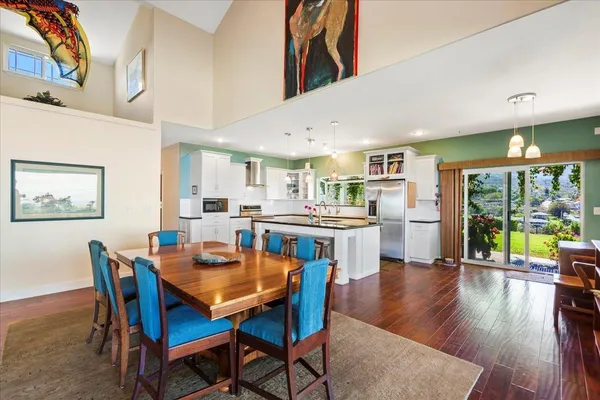 a dining room with stainless steel appliances kitchen island granite countertop a dining table chairs and view of living room
