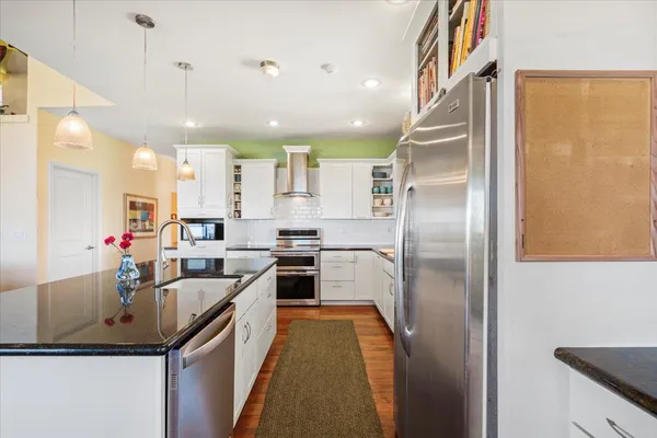 a kitchen with stainless steel appliances granite countertop a sink a stove and a refrigerator